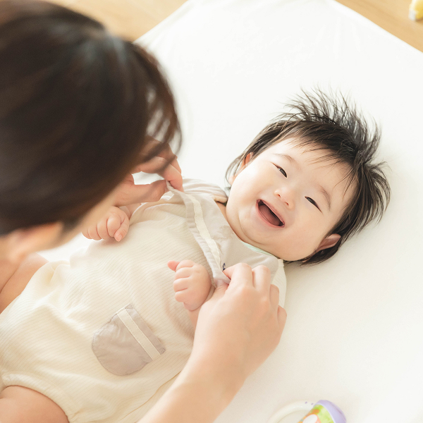 自宅のいつものお布団でママと触れ合っている時の赤ちゃんのリラックスした笑顔