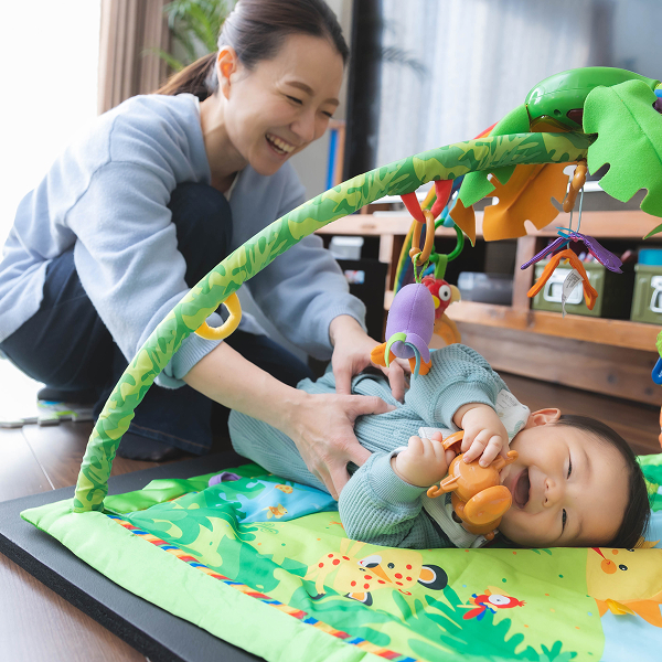 自宅のプレイマットでママと触れ合っている時の赤ちゃんの楽しい笑顔