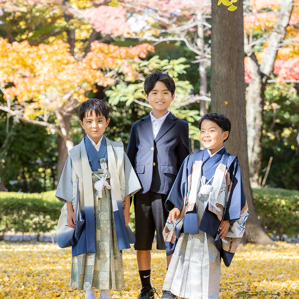紅葉する木々の中、着物やジャケットで正装した自然な笑顔の男の子3人