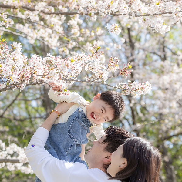 パパに「たかいたかい」をしてもらって、満遍の笑みで楽しむ男の子とそれを見上げる両親