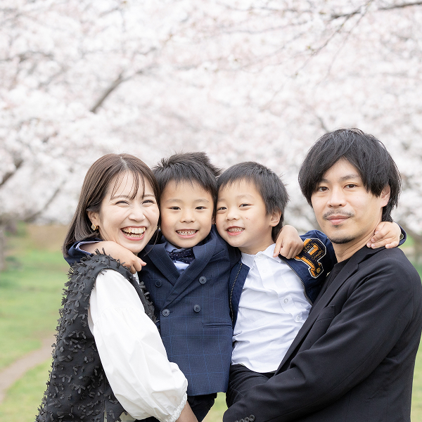 桜の風景を背景にした家族4人の笑顔の写真