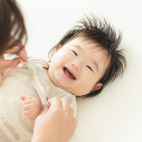 自宅のいつものお布団でママと触れ合っている時の赤ちゃんのリラックスした笑顔