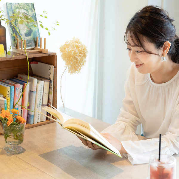 お花でオシャレに彩られたナチュラルな雰囲気のデスクで女性が読書をしている