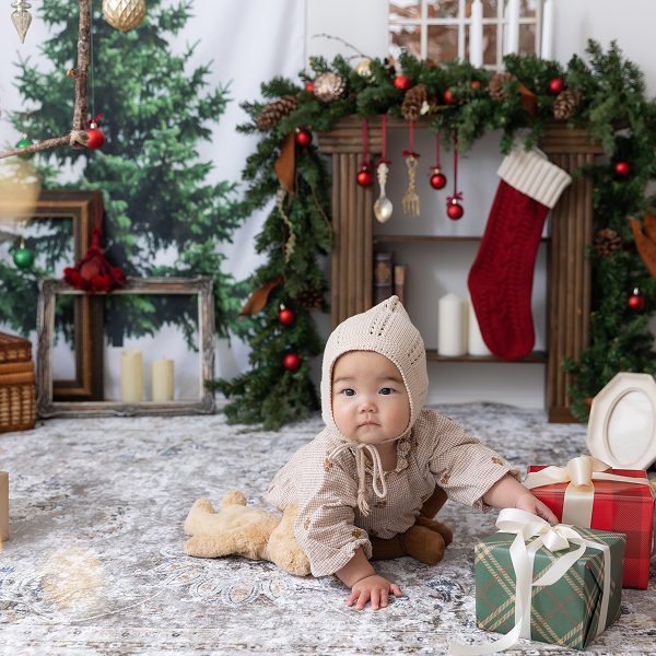クリスマス仕様のスタジオでプレゼントの箱に手をかけるハイハイの赤ちゃん