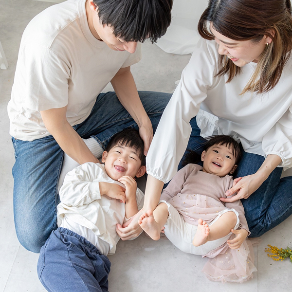 スタジオで幼い兄妹が両親の膝下に横になり遊んでいる